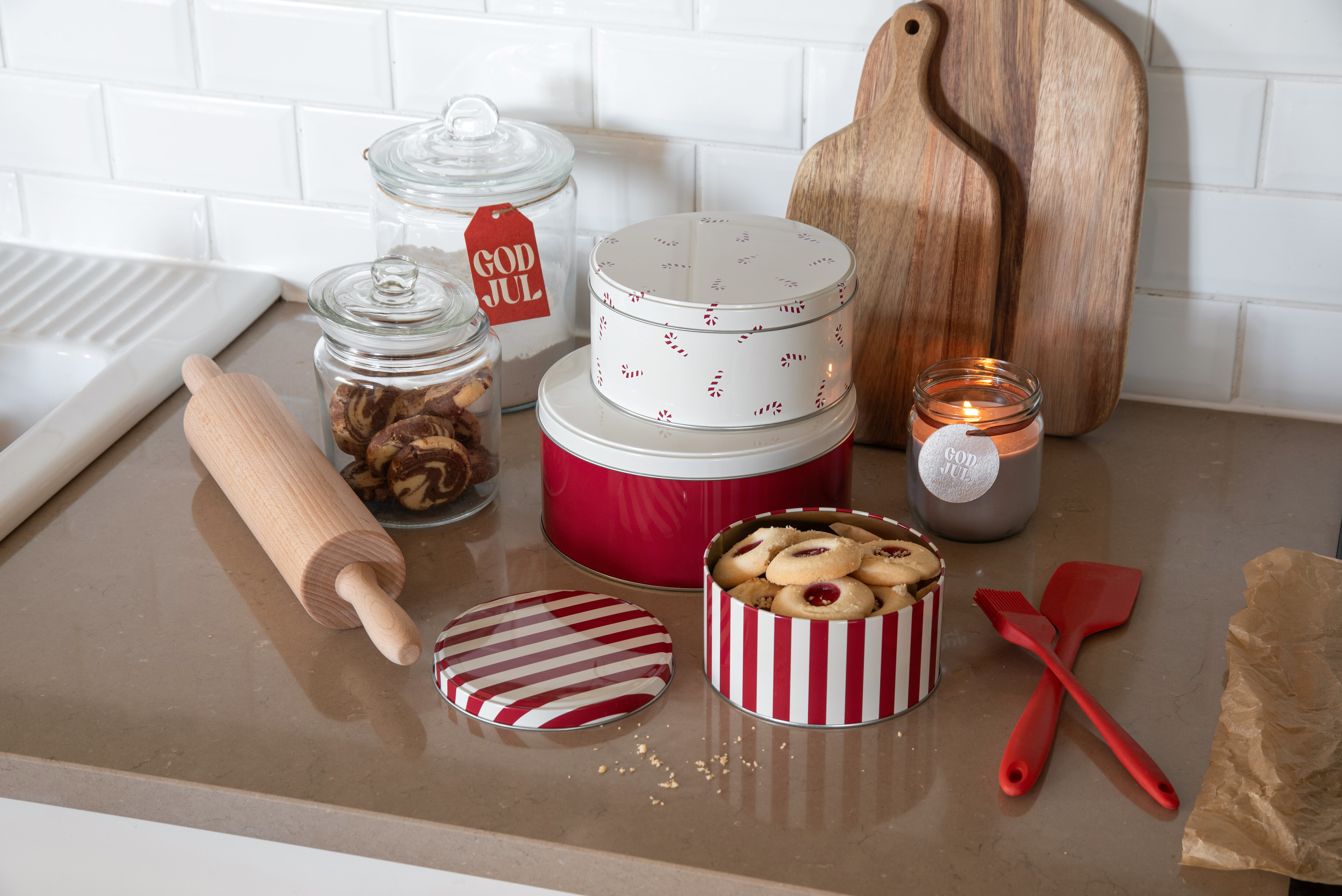 Julebakst med kakebokser, kjevle og pepperkakeformer på kjøkkenbenken.