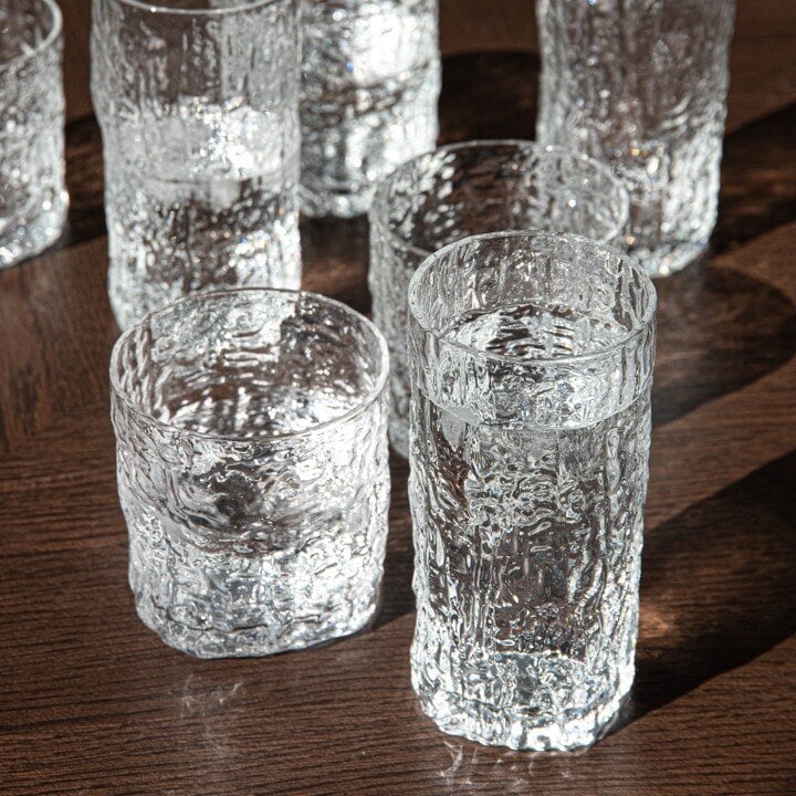 Strukturerade dricksglas i klarglas på ett träbord.
