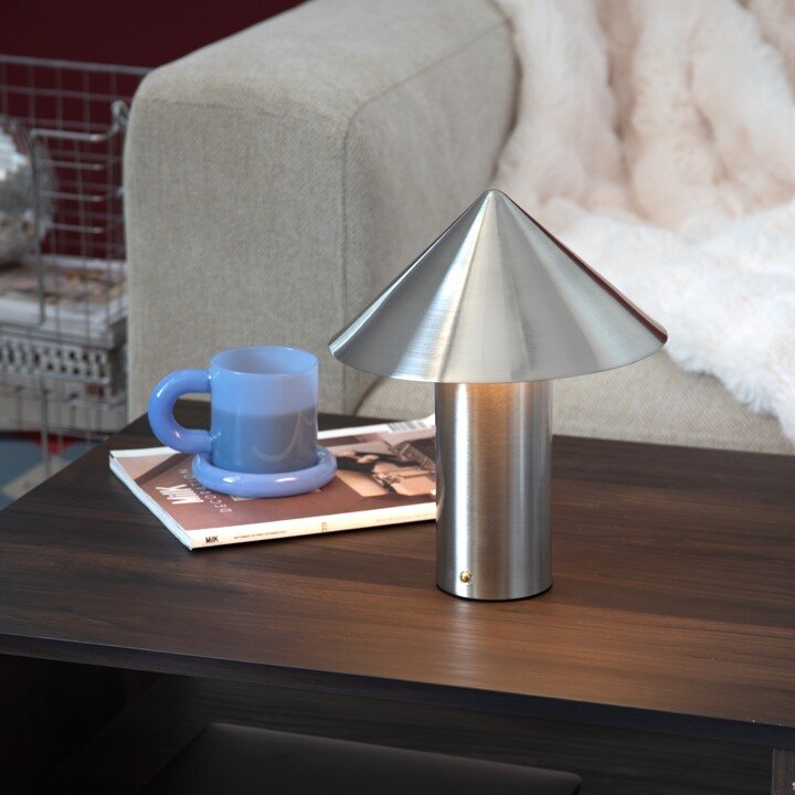 Bordslampa i metall på ett sidobord som present till honom.