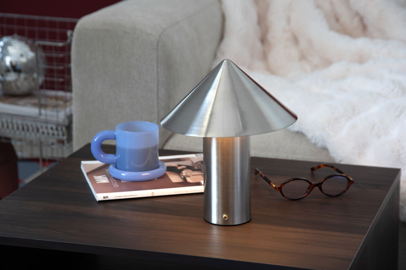Metallisk lampe stående på et bord.