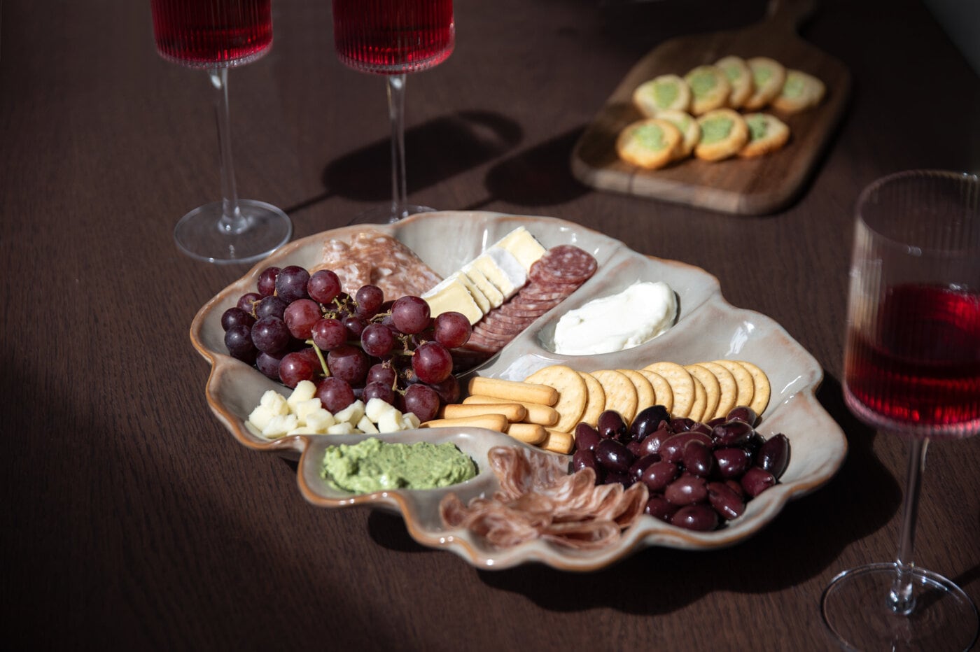 Serveringsfat med ost, chark, kex och vindruvor uppdukat som inspiration för middagar och presenter.