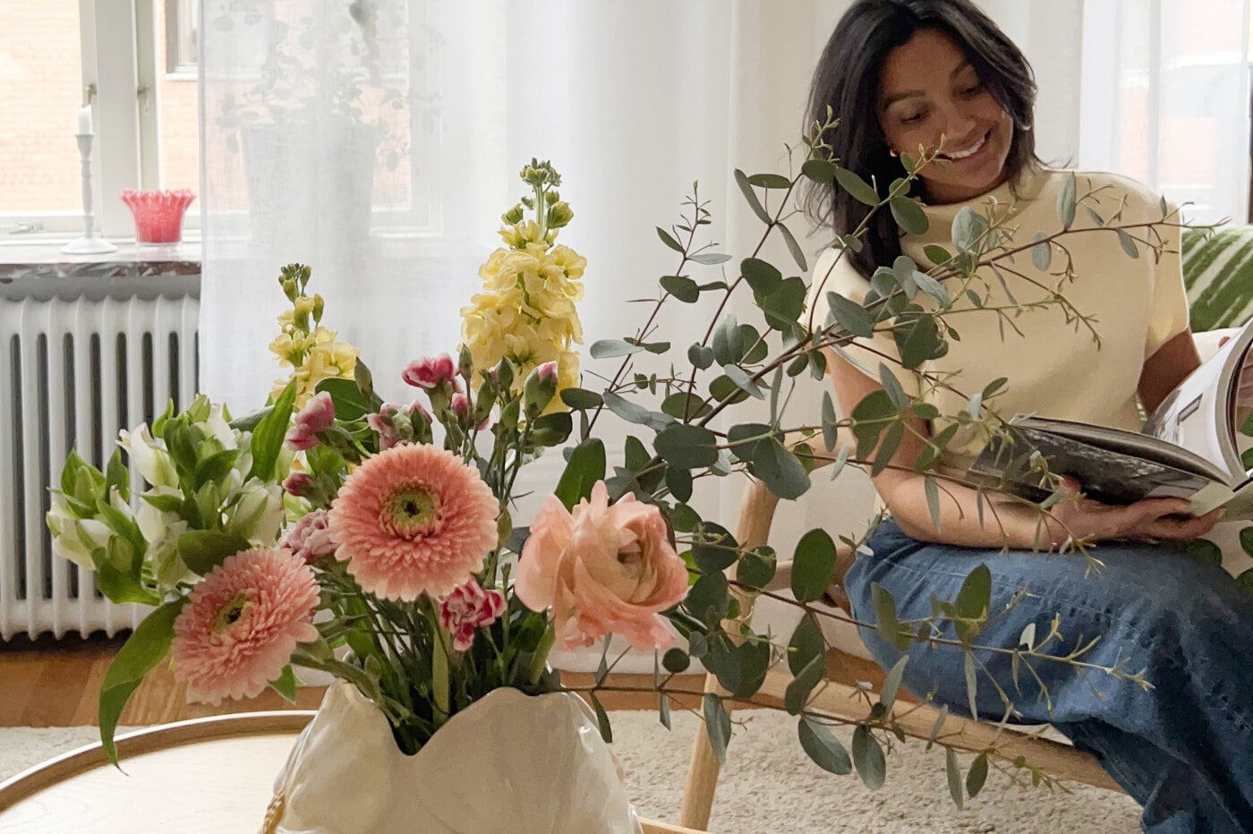 Rosa vas med blommor och färgade ljuslyktor i på bord.