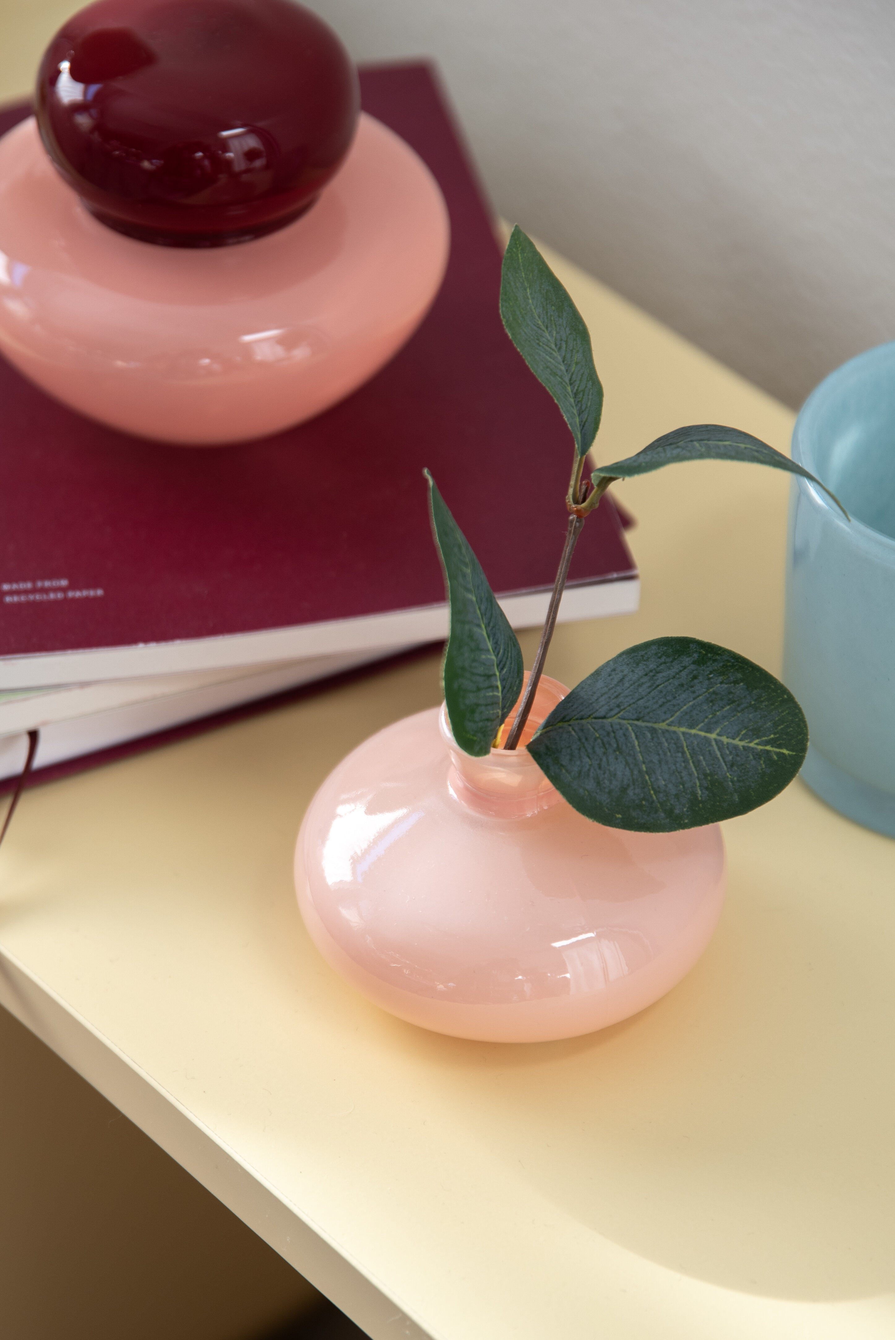 Ljuslyktor i glas i olika färger mot vinröd bakgrund