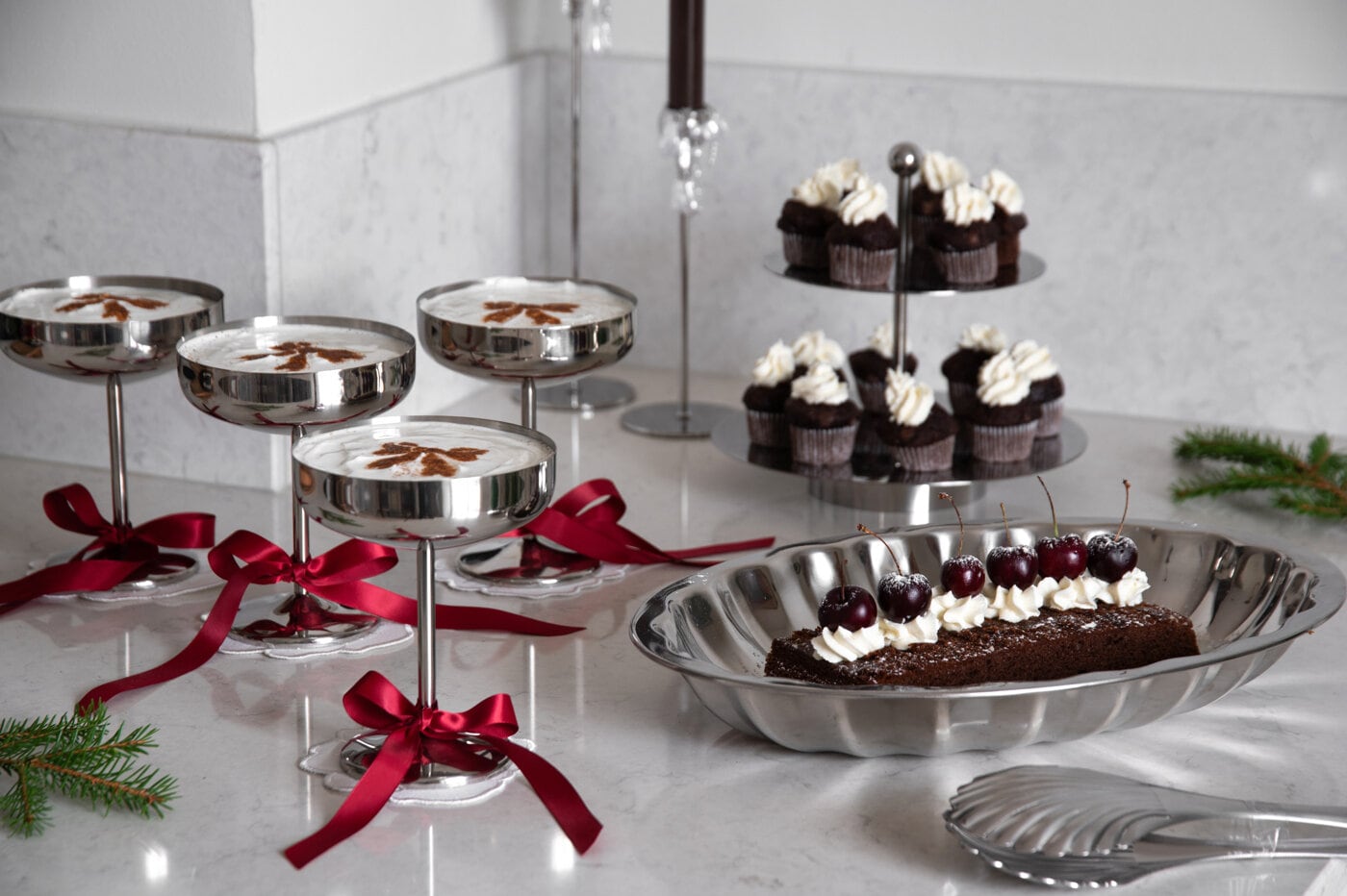 Trendy julepyntet dessertbord med sjokoladekake, cupcakes og drinker dekorert med burgunderrøde sløyfer.