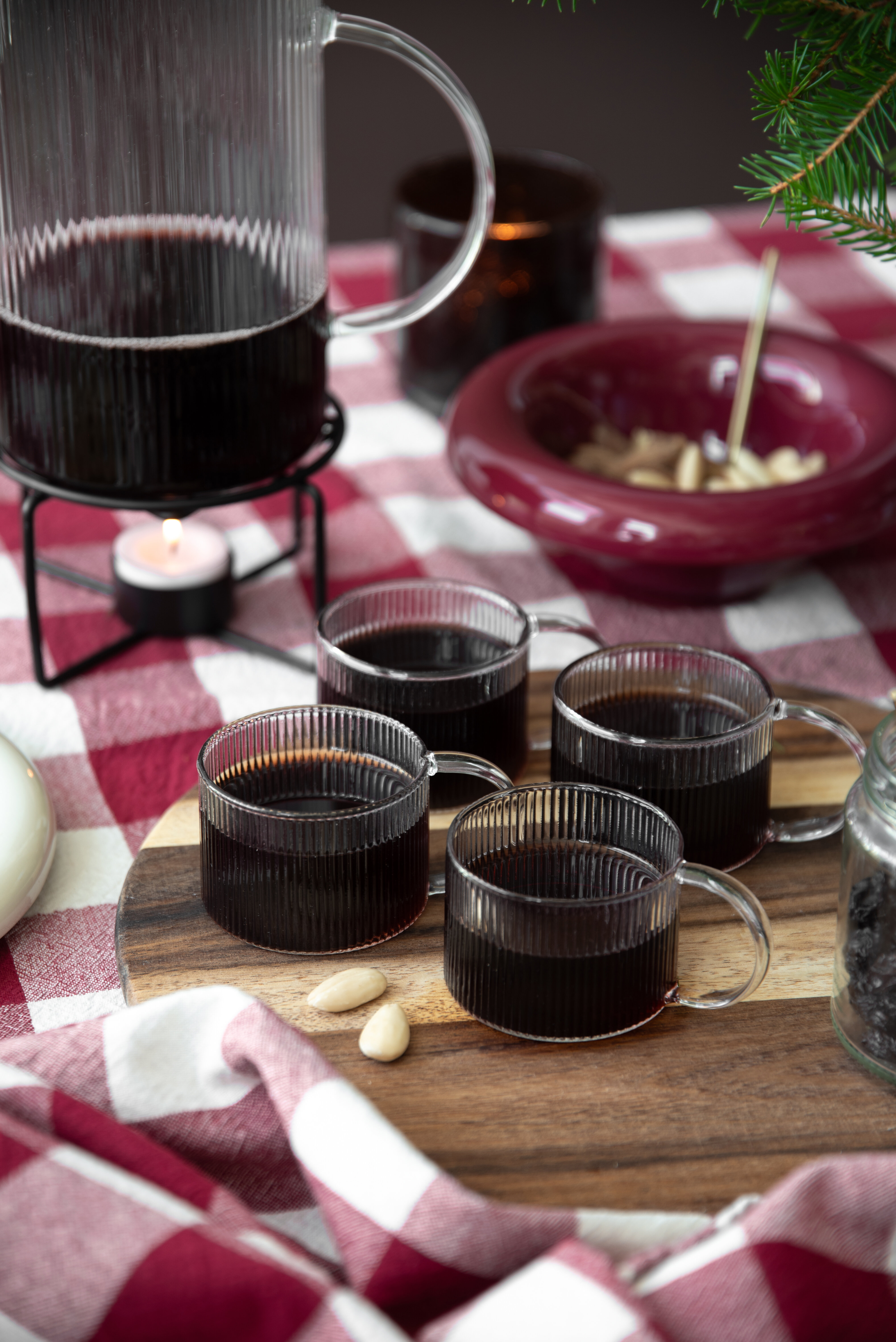 Muggar med glögg på en juldukning i röda toner.