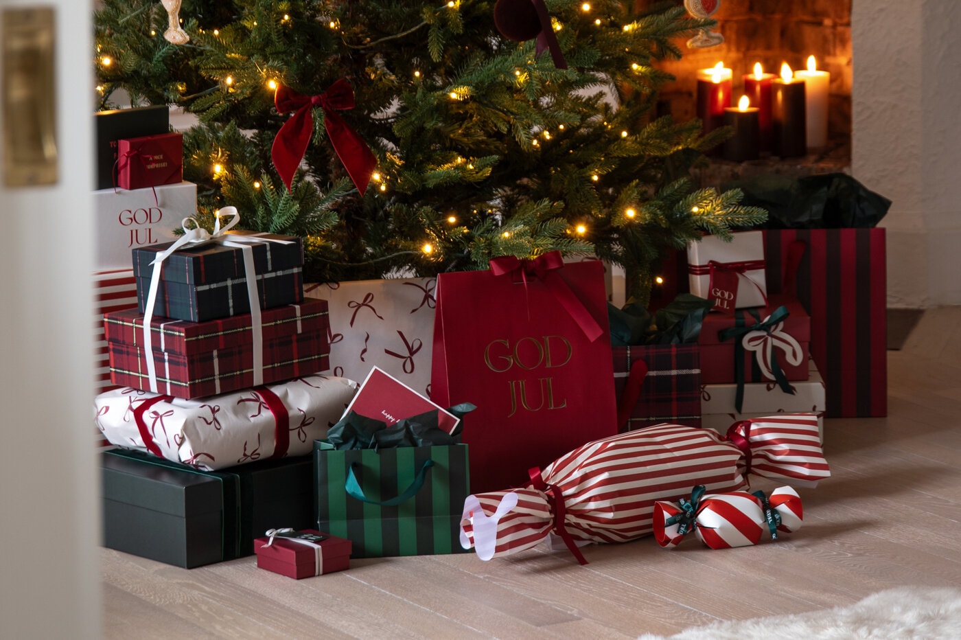 Inslagna julklappar i rött, grönt och rutigt under en pyntad julgran