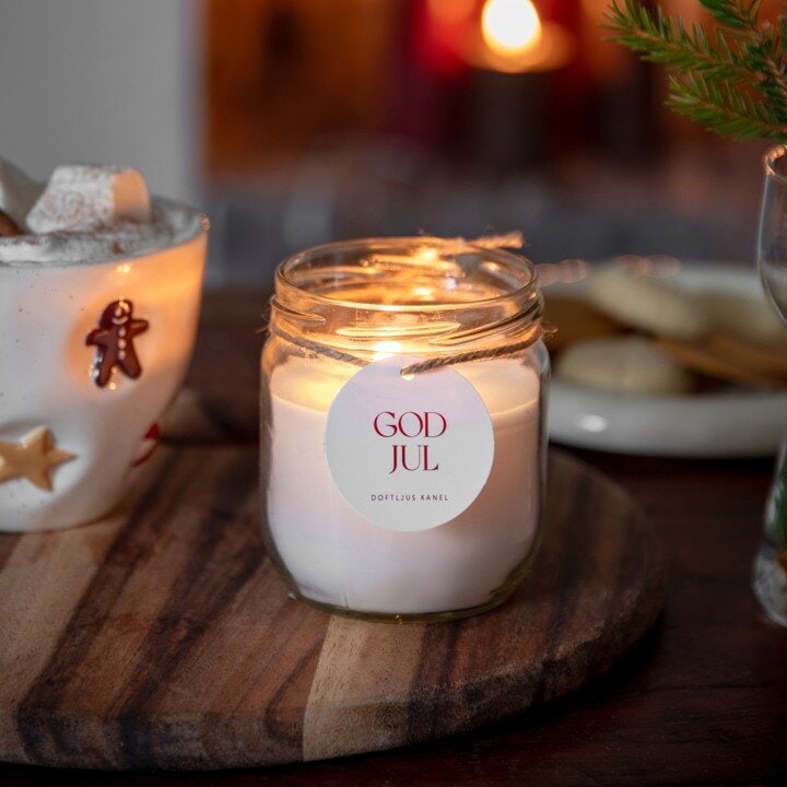 Tent duftlys med kanelduft og teksten «God jul» på et trefat.