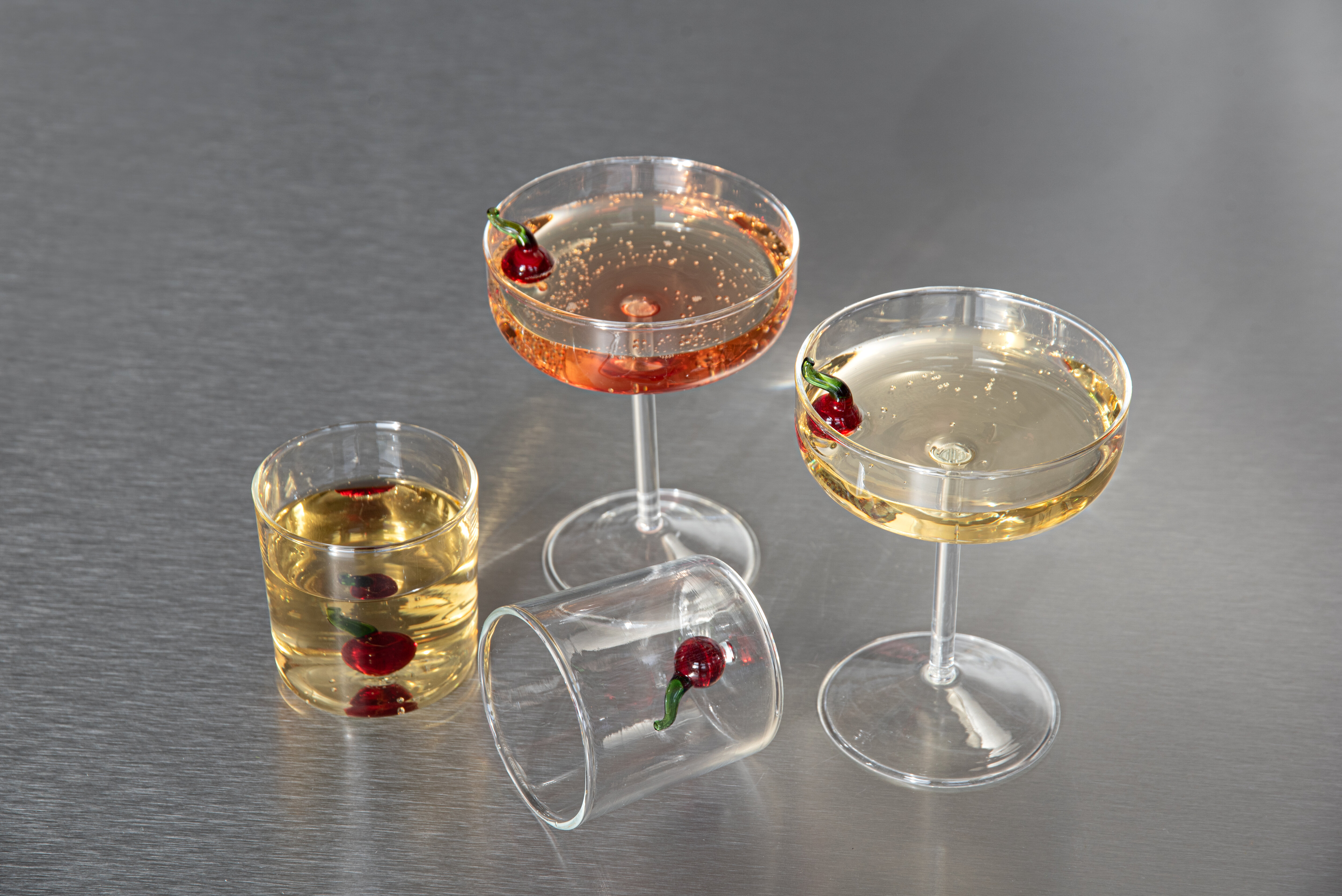 Klare glass med kirsebærdekor og drikke på et metallbord.