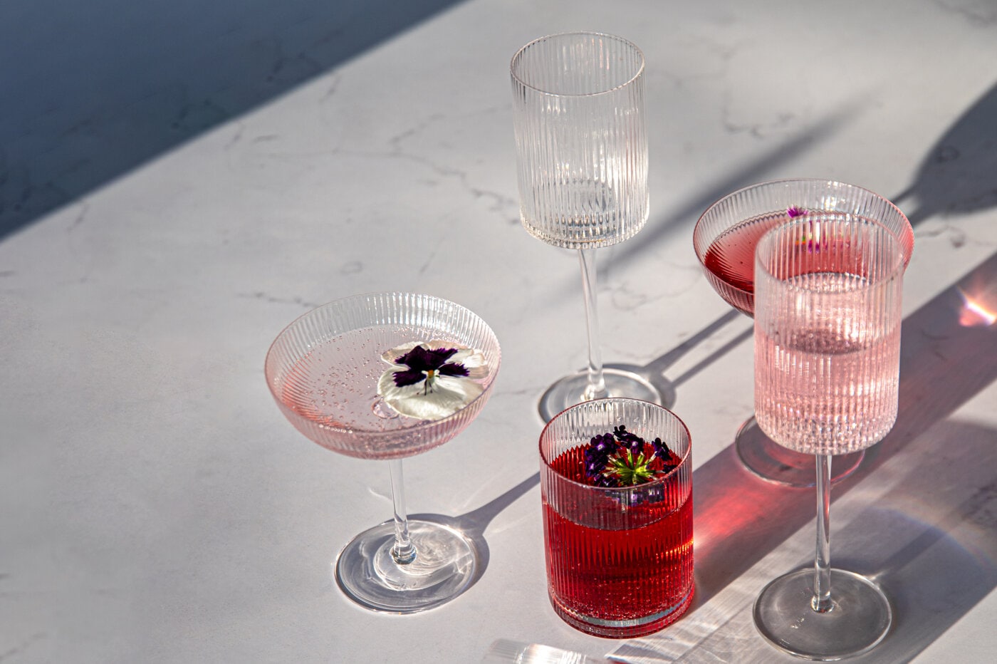 Fire Ribbed drikkeglass i klart, rillet glass, ett med rød sløyfe, mot rød bakgrunn.