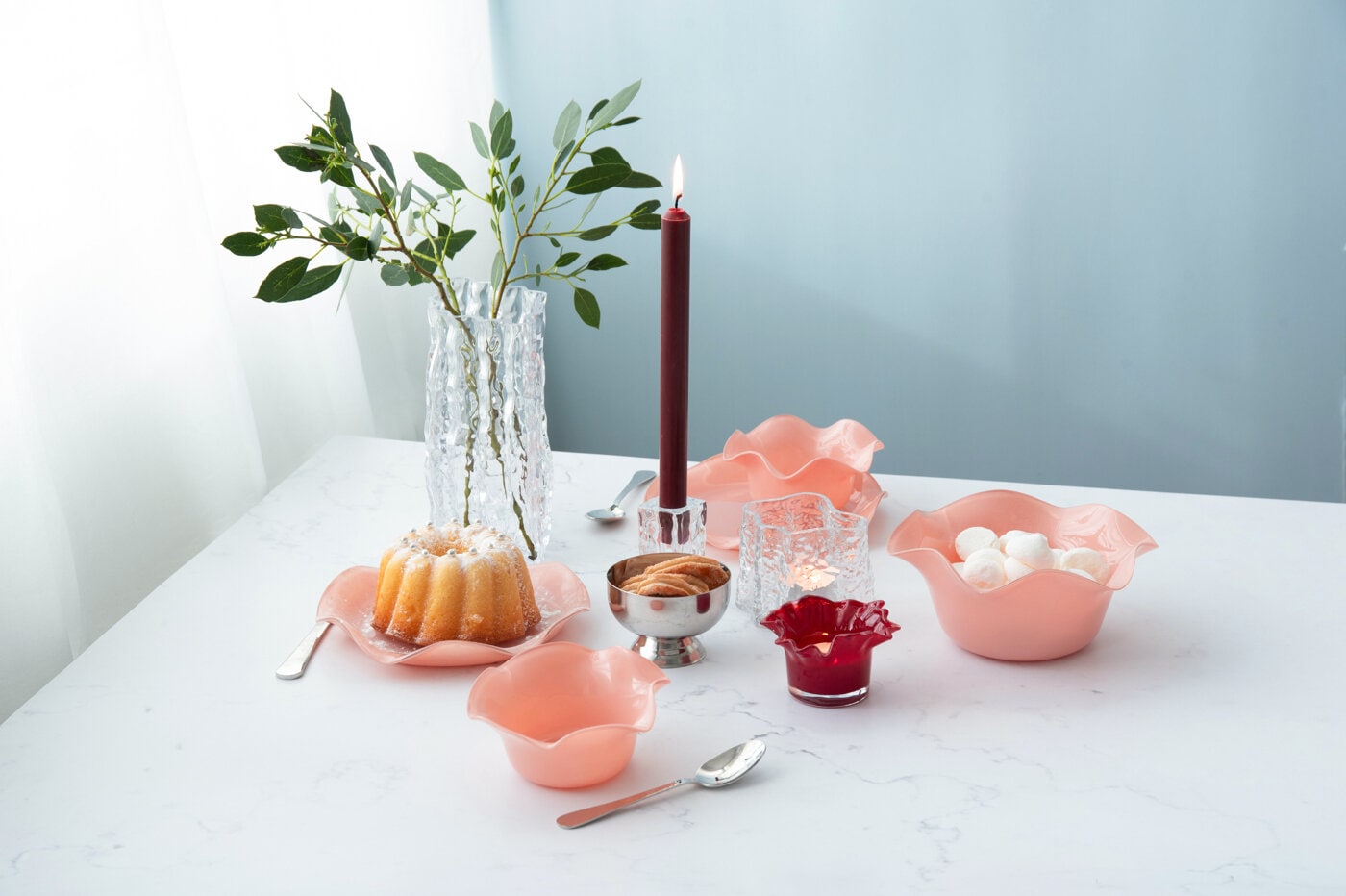 Borddekking med lys, kake og serveringsskåler i rosa.