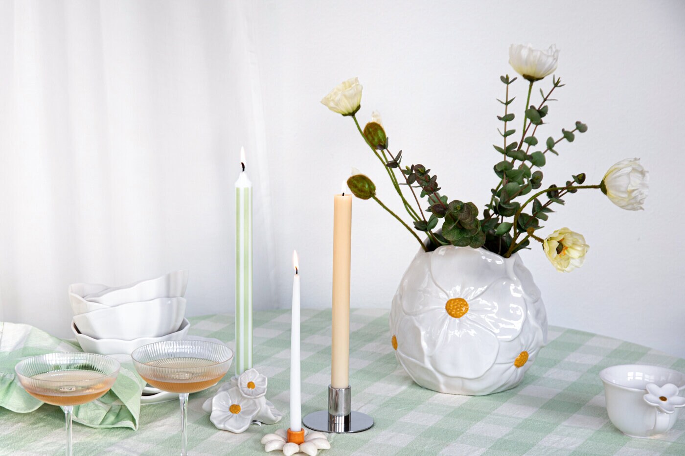 Hvit vase med blomster på et vårdekket bord