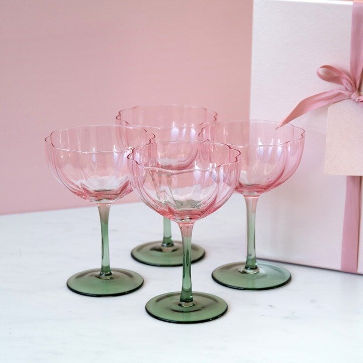 Champagneglass Blomma stående mot rosa bakgrunn.