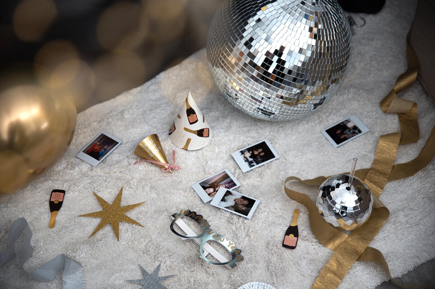 Partyhattar, foton och discokulor på matta efter nyårsfest.