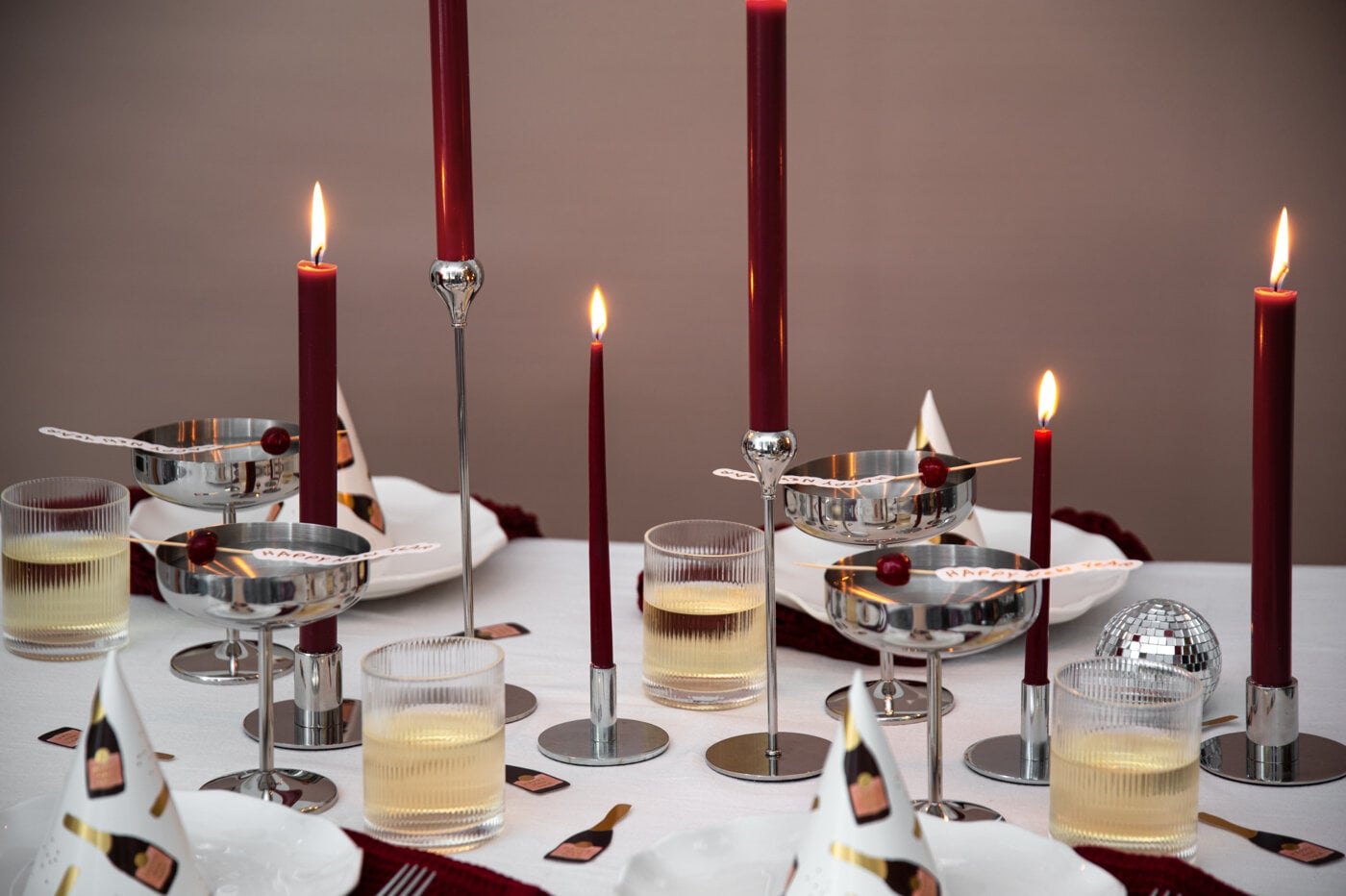 Dukat bord med röda ljus i silverljusstakar, glas med dryck och dekorationer.