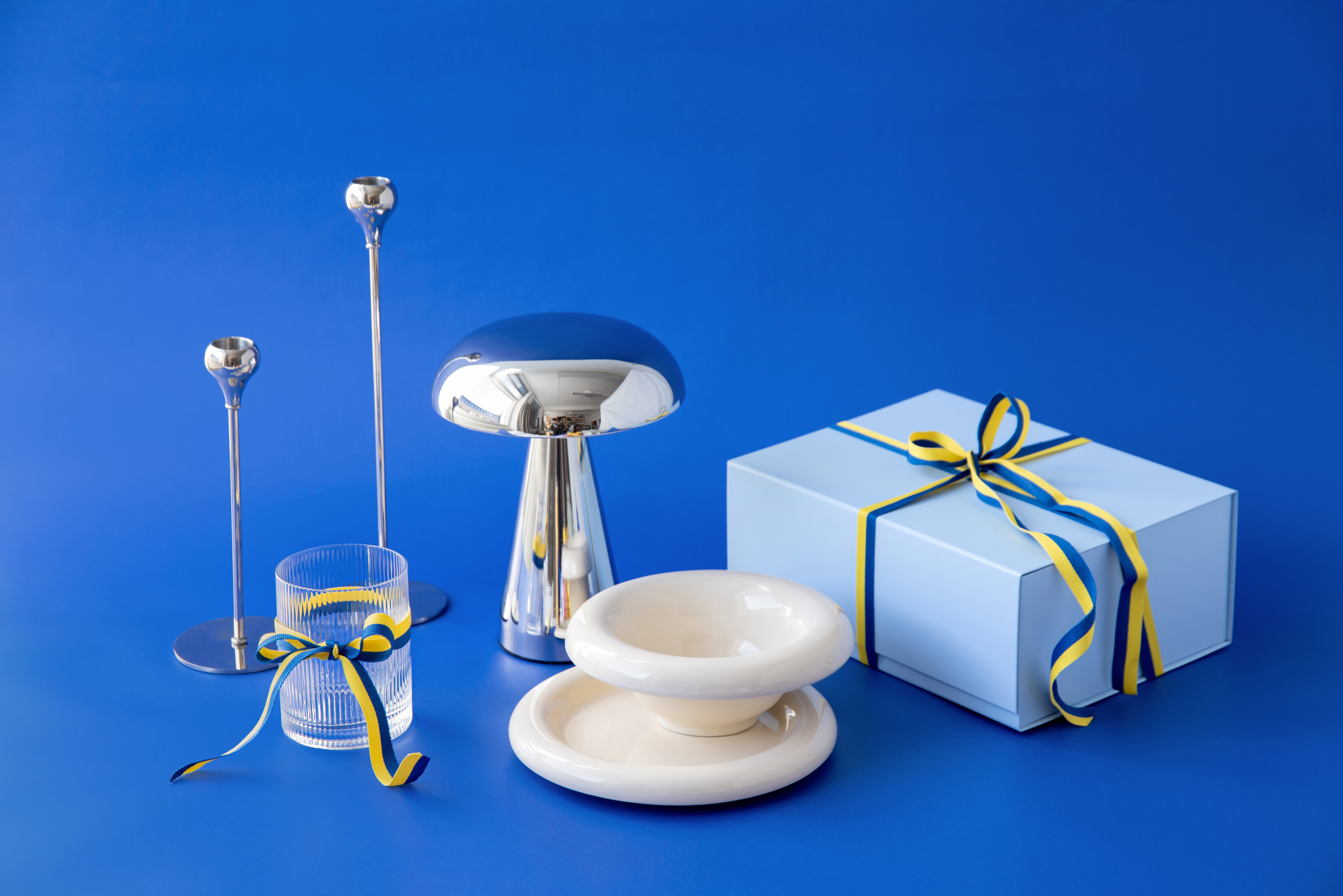 Gaveeske og kake på blå bakgrunn med dekorative festdetaljer.