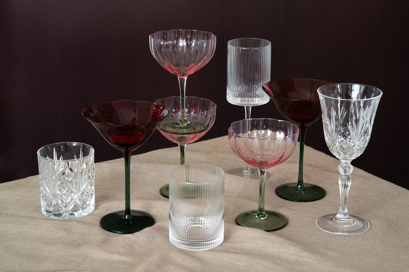 Ulike drikkeglass og cocktailglass i klart, rosa og burgunderrødt glass.