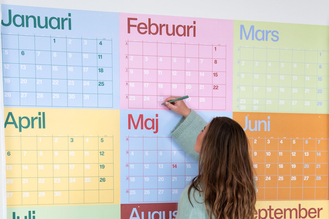 Person som skriver i en stor, fargerik veggkalender.